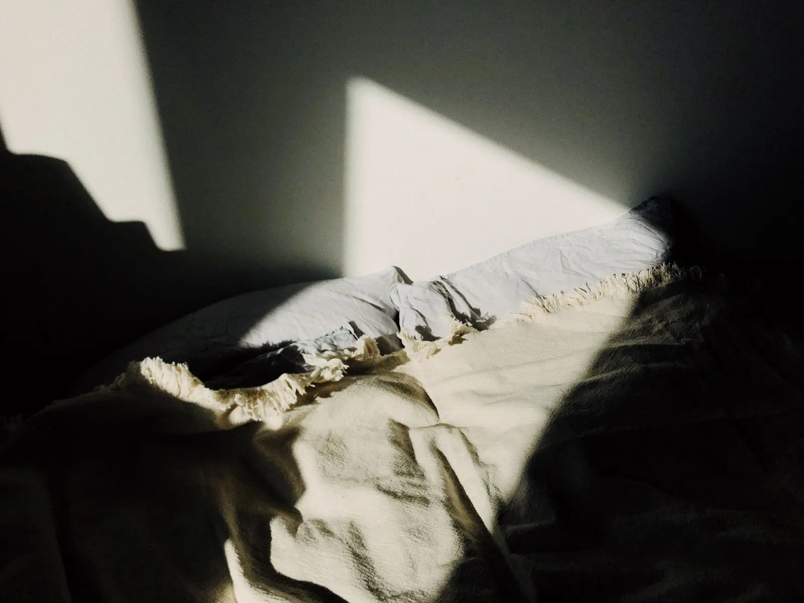 Recámara con la cama tendida e iluminada por la luz de la mañana.