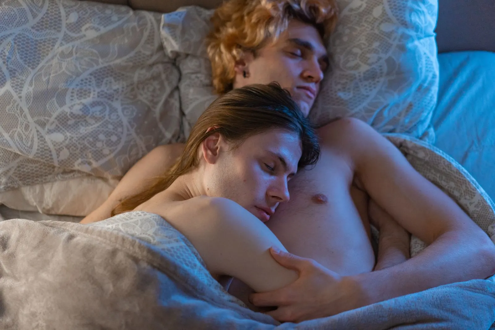 Pareja durmiendo en una cama en una recámara con luz tenue de noche.